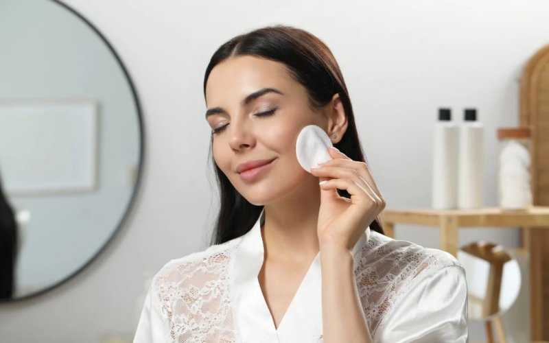 Lau khô da mặt với bông tẩy trang.